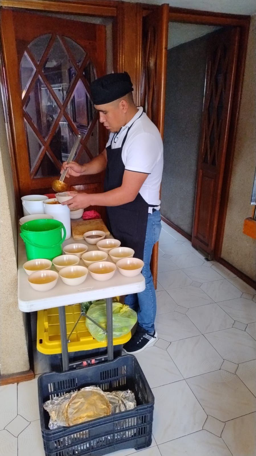 Cocinero sirviendo consomé con un cucharón en tazones durante un evento