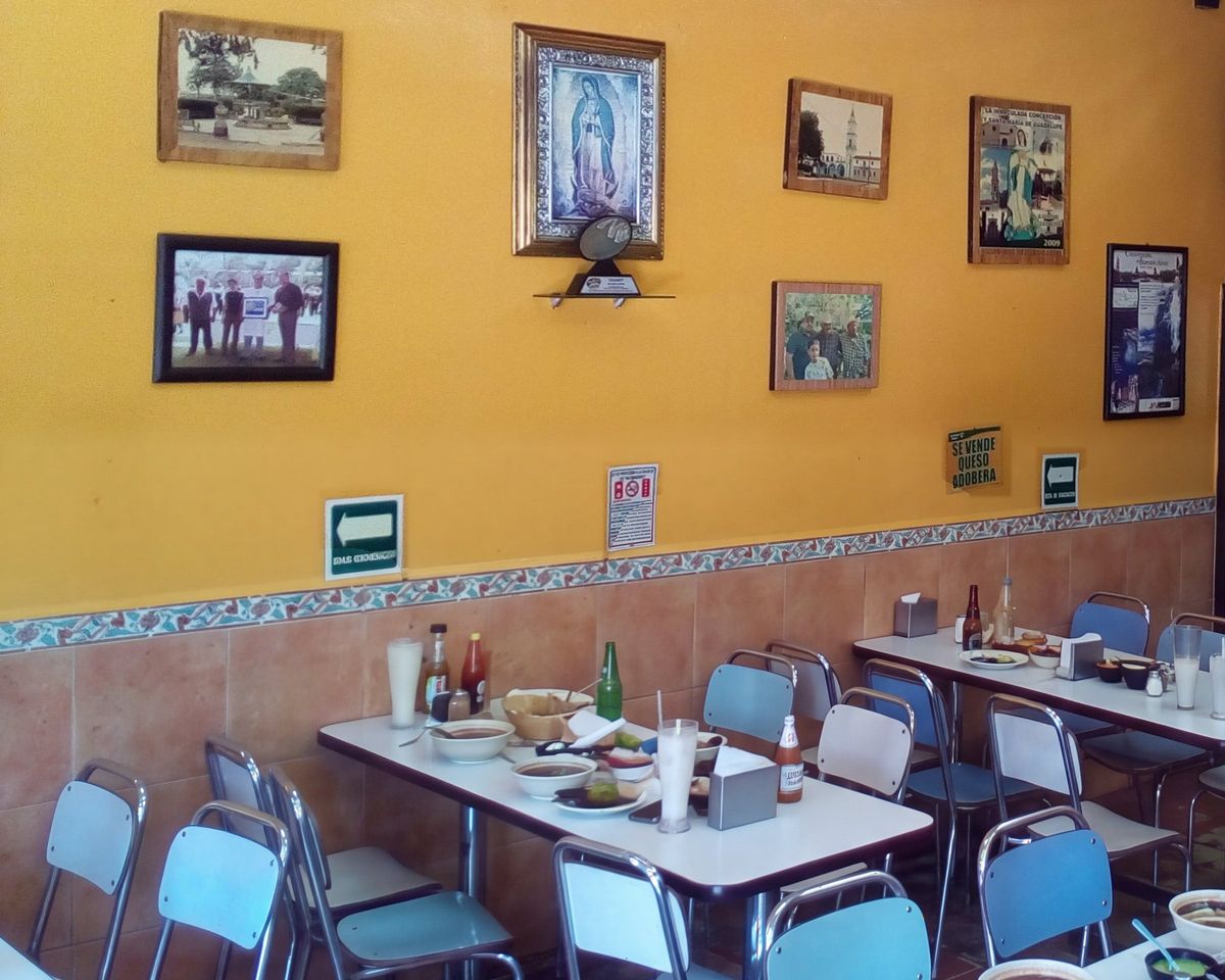 Mesas servidas y sillas azules junto a la pared amarilla del comedor